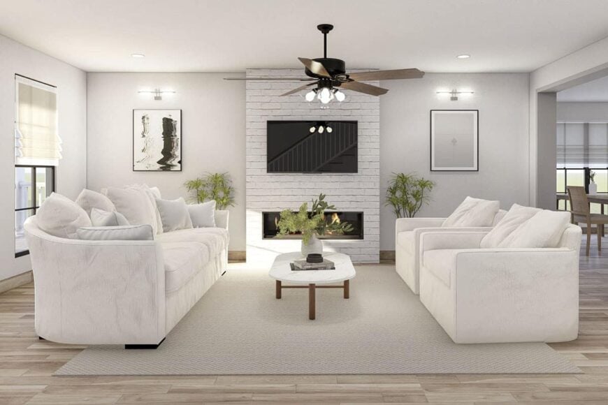 Great room with facing white seats and a fireplace topped with a TV.