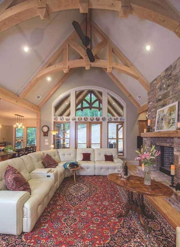 Lodge room with a leather tufted sofa, a brick fireplace, and a cathedral ceiling framed with exposed trusses.