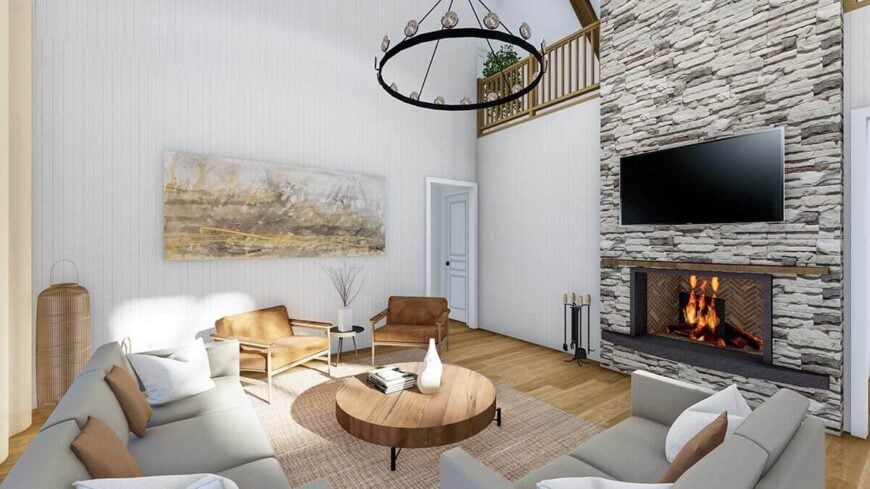 Great room with gray sectionals, brown armchairs, and a stone fireplace topped with a wall-mounted TV.