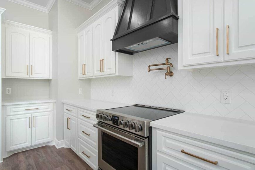 Brass fixtures and hardware add elegance to the white kitchen.