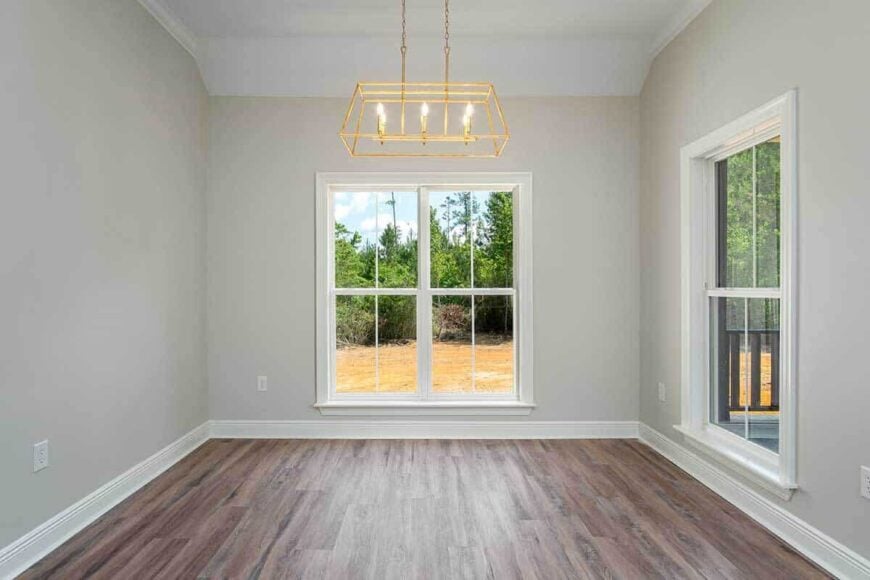 Dining area with a linear chandelier and a large window that looks out the backyard.