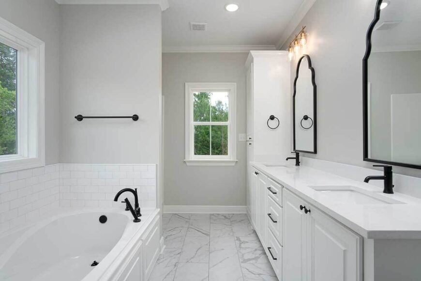 The primary bathroom has a marble tiled floor, a dual sink vanity, and a deep soaking tub.