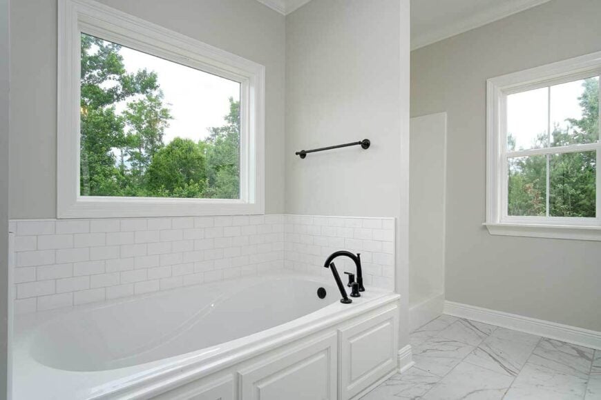 A picture window and wrought iron towel rack top the drop-in bathtub.