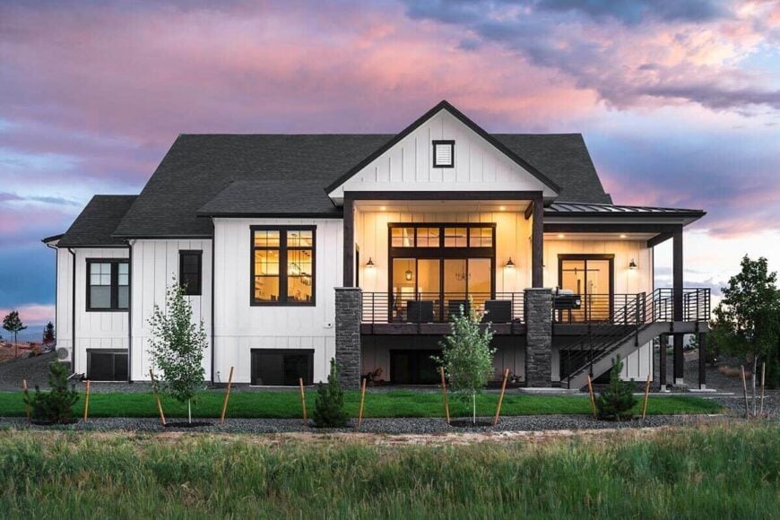 Rear exterior view showcasing a spacious covered deck supported by stone pillars.