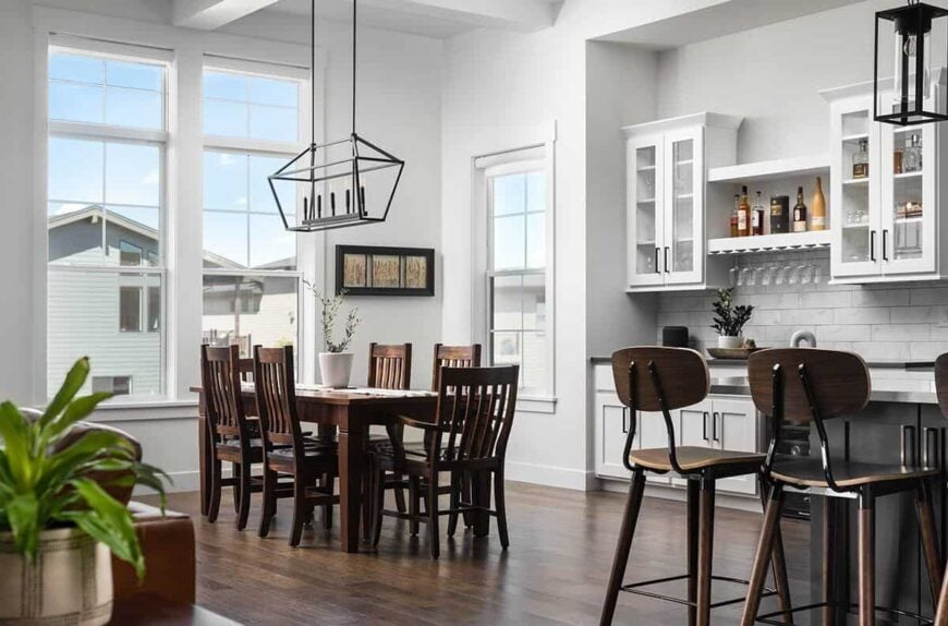 The dining area is brightened by large windows and a wrought iron chandelier that hangs over the wooden dining set.