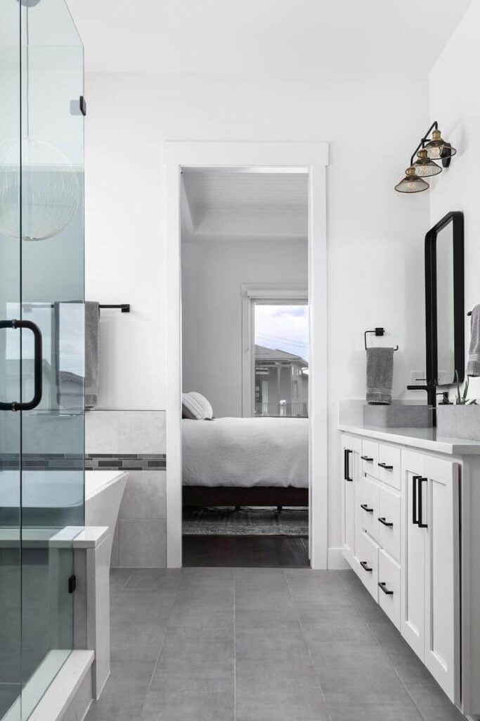 The primary bathroom has a walk-in shower, a freestanding tub, and a white vanity with double vessel sinks and iron-framed mirrors.