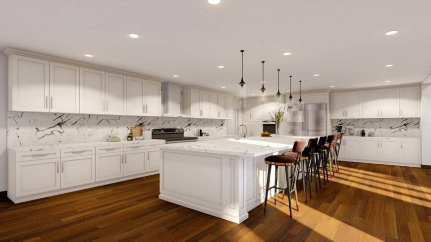 An enormous kitchen space filled with white cabinetry, a lengthy island, and a marble backsplash that matches the countertops.