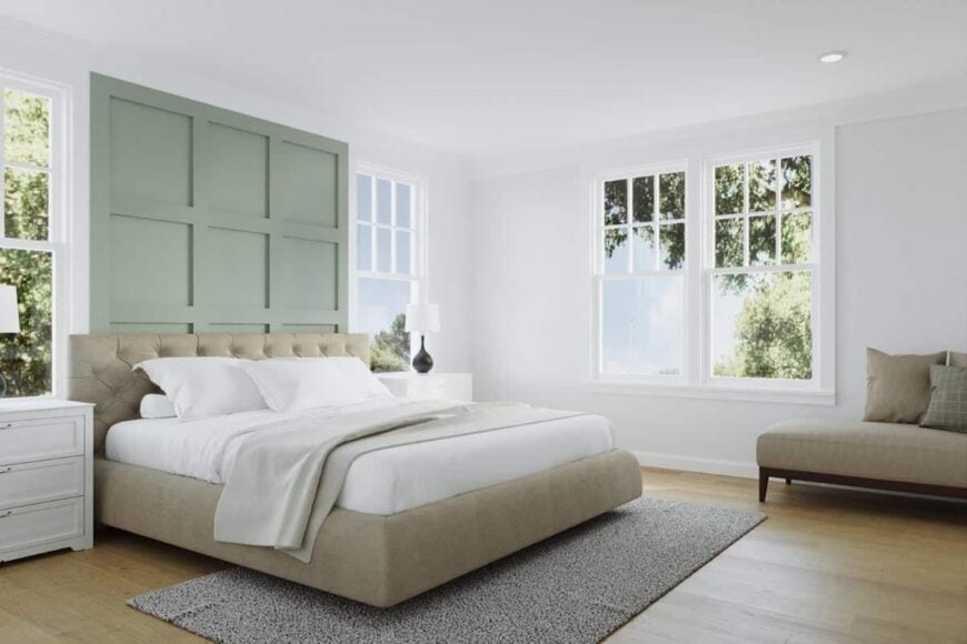 The primary bedroom has hardwood flooring and a tufted bed highlighted by a sage green paneled accent wall.