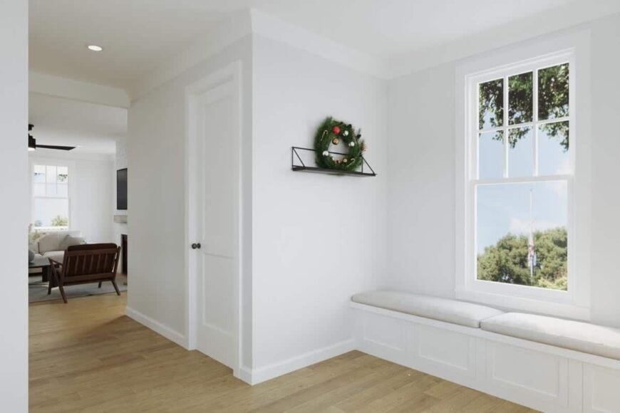 A sitting area by the window with a built-in bench topped with beige cushions.