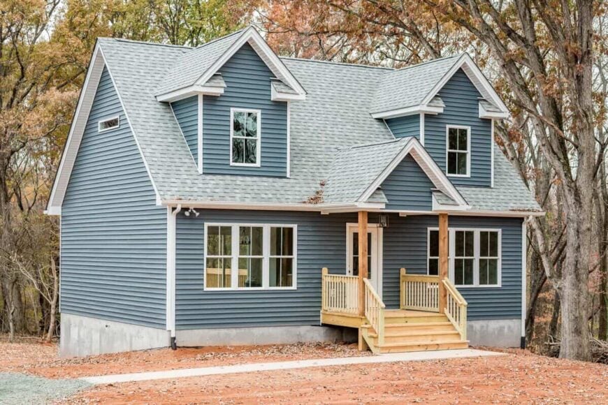 Front exterior view showcasing its blue horizontal lap siding, gable dormers, and a central covered entry.