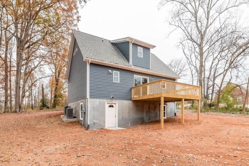 Rear exterior view with a shed dormer and a sun deck bordered by wooden railings.