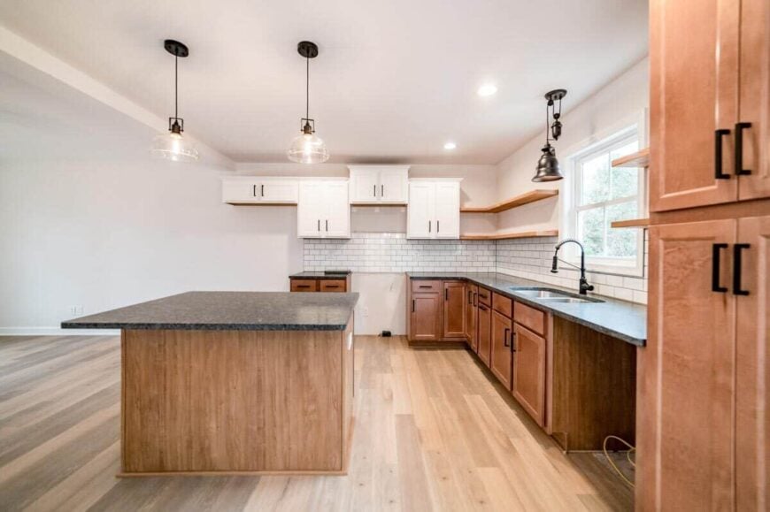 A tray ceiling fitted with recessed lights and glass pendants crowns the kitchen.