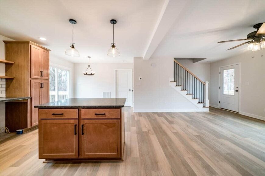 An open layout view of the kitchen, dining area, and family room well-lit by warm lighting fixtures.