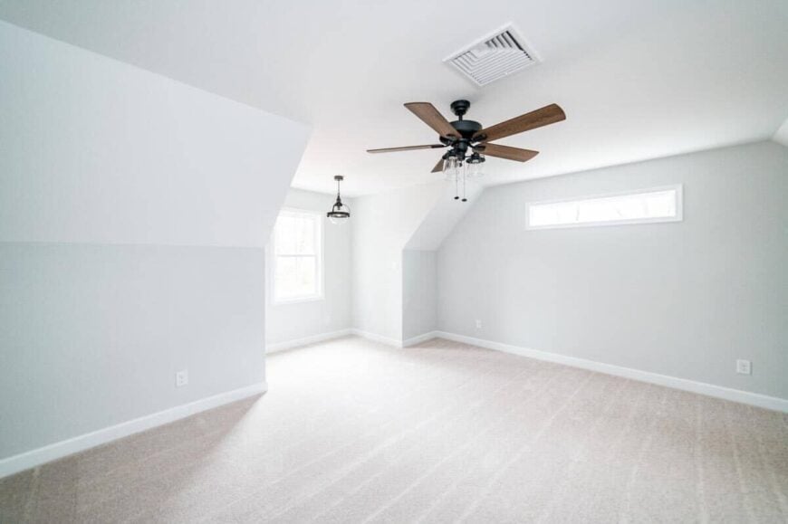 Another bedroom with carpet flooring and white framed windows inviting natural light in.