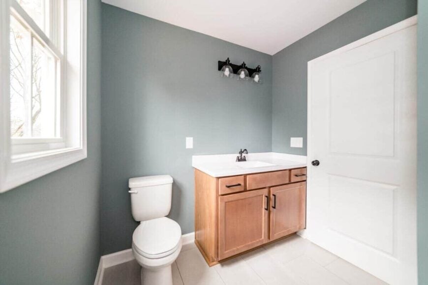 Bathroom with a toilet and a single-sink vanity fixed against the gray walls.