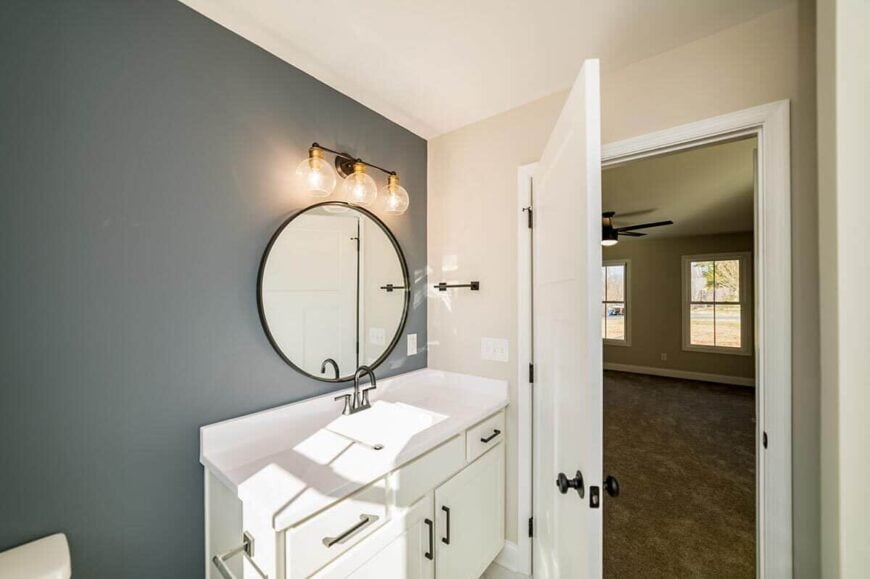 A gray accent wall adds a nice contrast to the white bathroom.