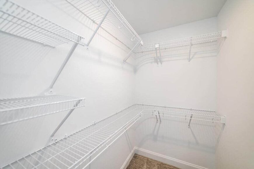 The primary walk-in closet is filled with white metal shelves.