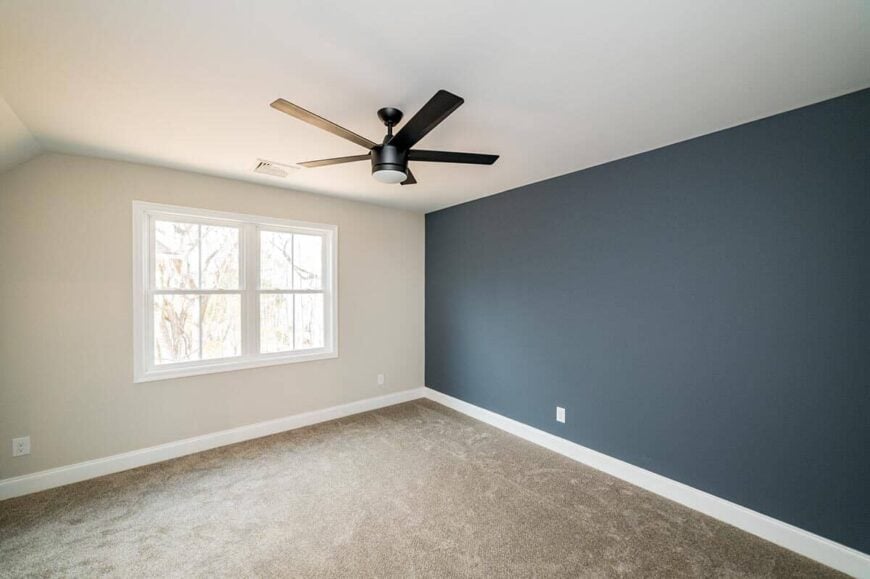The deep blue accent wall in the primary suite is mirrored in this bedroom.