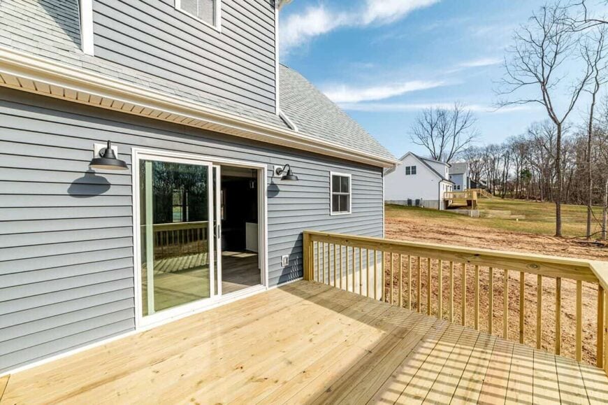 A large, grilling deck with wooden railings overlooks the expansive yard.