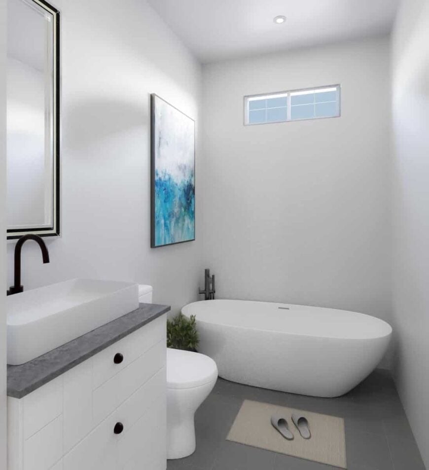 This bathroom offers a freestanding tub and a white vanity topped with a vessel sink.