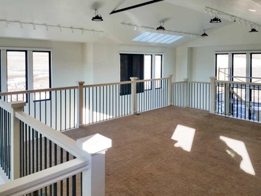 Wrought iron railings with white posts and handrails border the studio loft.