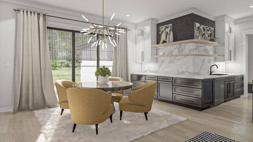 The breakfast nook is furnished with contemporary armchairs and a round dining table topped with a brass chandelier.