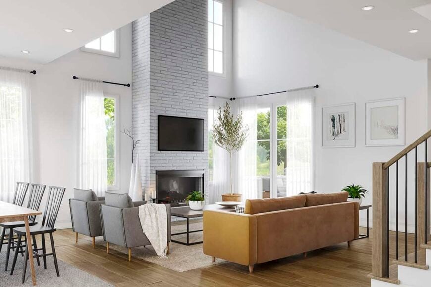 The living room has a two-story ceiling, a brown sofa, and a brick fireplace with a TV on top.