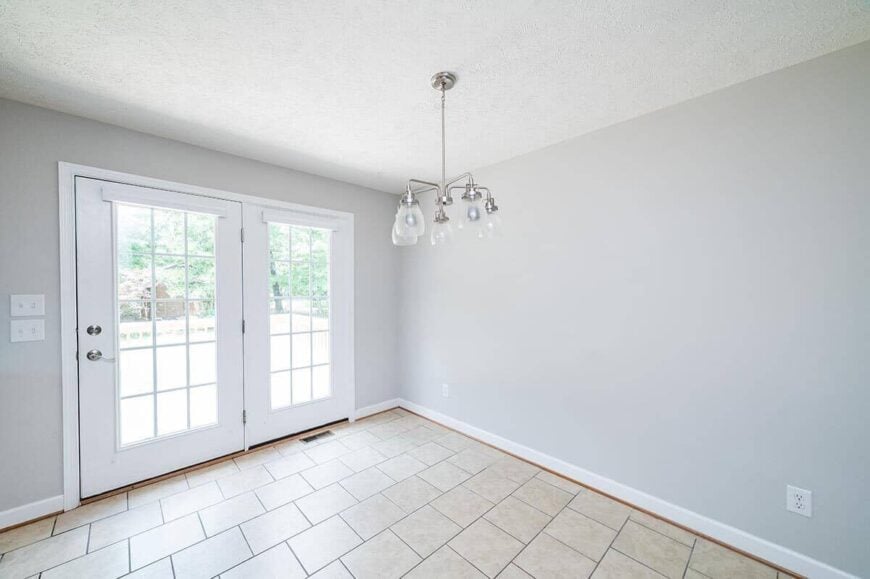 The dining area has tiled flooring, a chrome chandelier, and a glazed door that opens to the rear deck.
