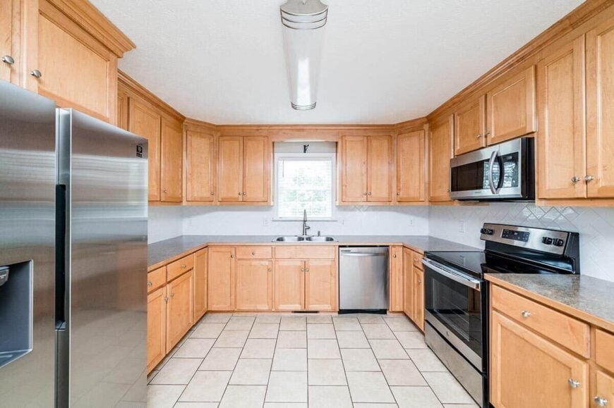 The kitchen is equipped with stainless steel appliances, double sinks, wooden cabinetry, and granite countertops.