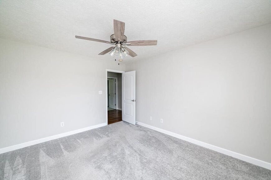 Primary bedroom with carpeted floor and gray walls lined with white base moldings.