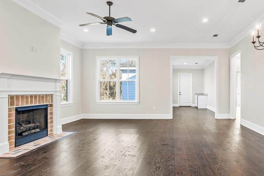 The living room has a fireplace and a ceiling fan. An open doorway on its side leads to the sunroom.