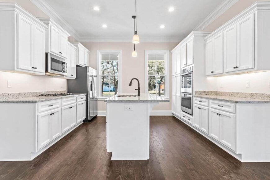 Kitchen with granite countertops, white cabinetry, and a center island.