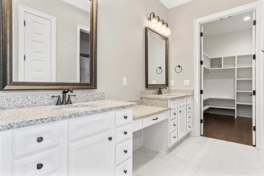 Primary bathroom with a walk-in closet and a dual sink vanity integrated with a makeup counter in the middle.