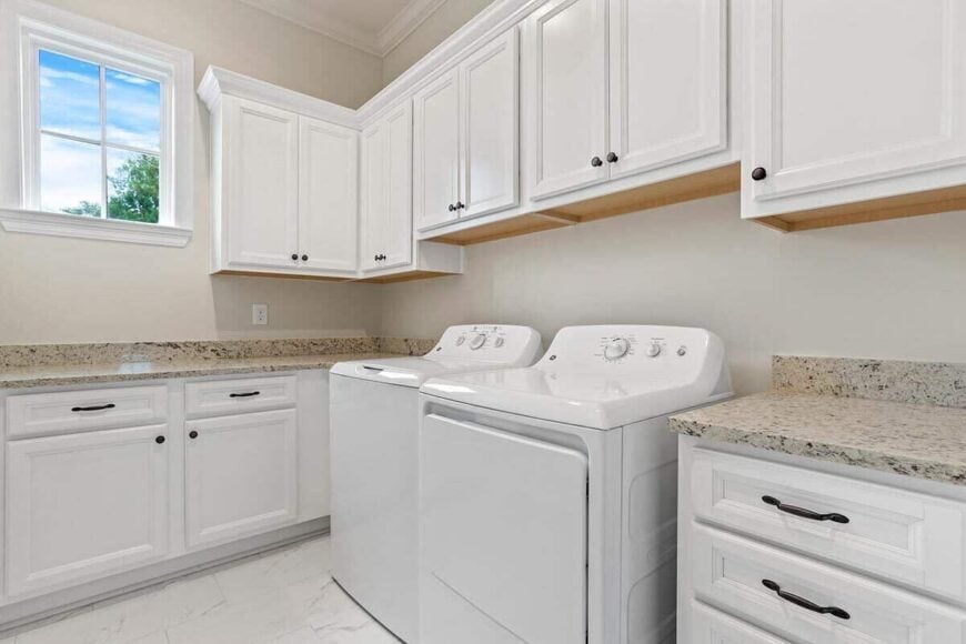 Laundry room with white washer and dryer, granite countertops, and plenty of storage.