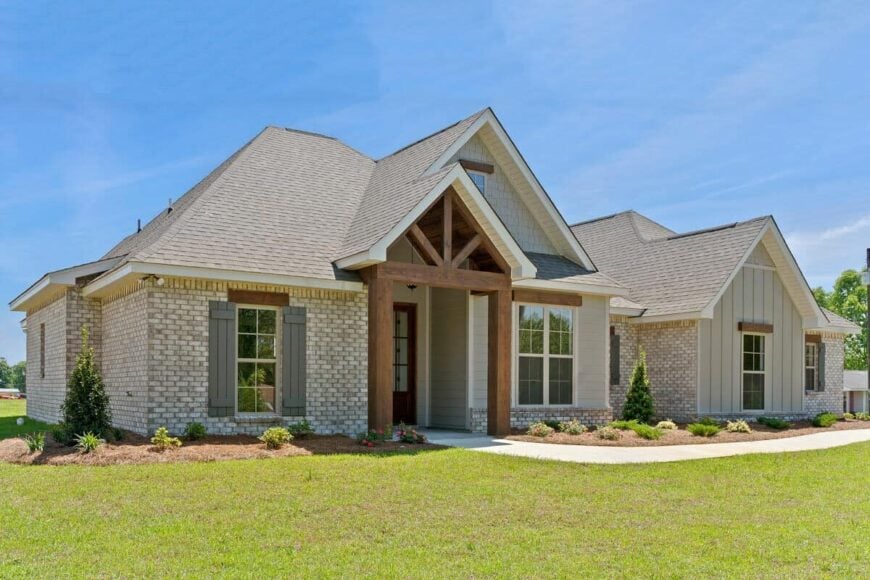 Front exterior view with brick and vertical siding, gable rooflines, and rustic timbers accentuating the windows and covered entry.