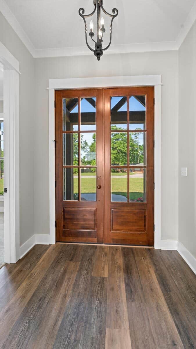 The foyer has a french front door and a wrought iron pendant light.