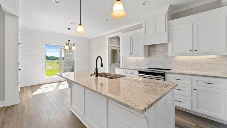 The kitchen island is equipped with double sinks and an eating bar.