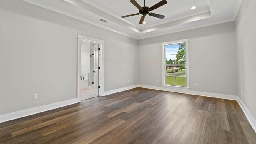 Primary bedroom with a tray ceiling, hardwood floor, and a window that invites natural light in.