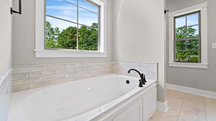 Primary bathroom with a freestanding tub fitted with wrought iron fixtures.