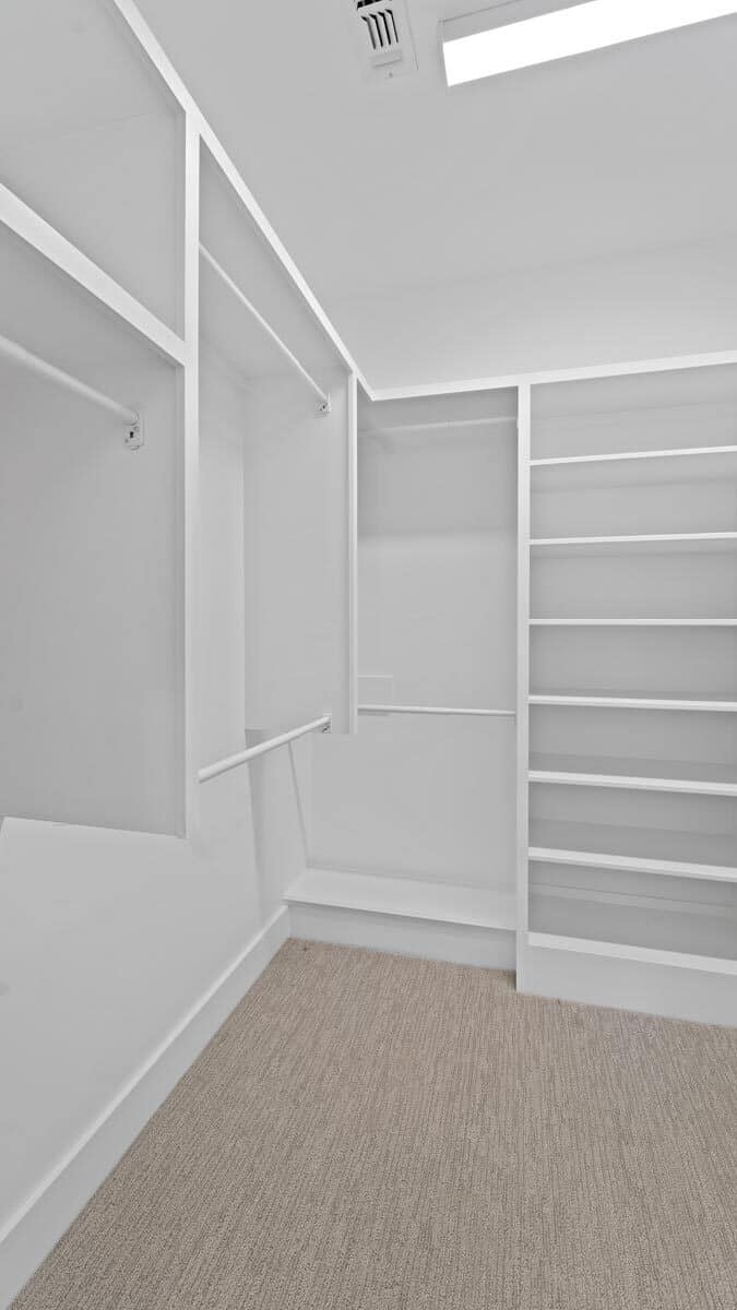 The primary walk-in closet has carpeted floor and built-in shelves.