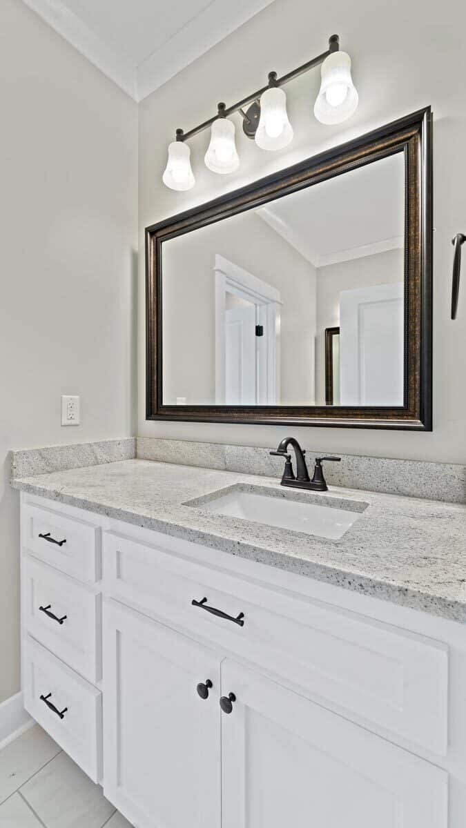 Wrought iron fixtures and hardware contrast the white cabinets and walls.