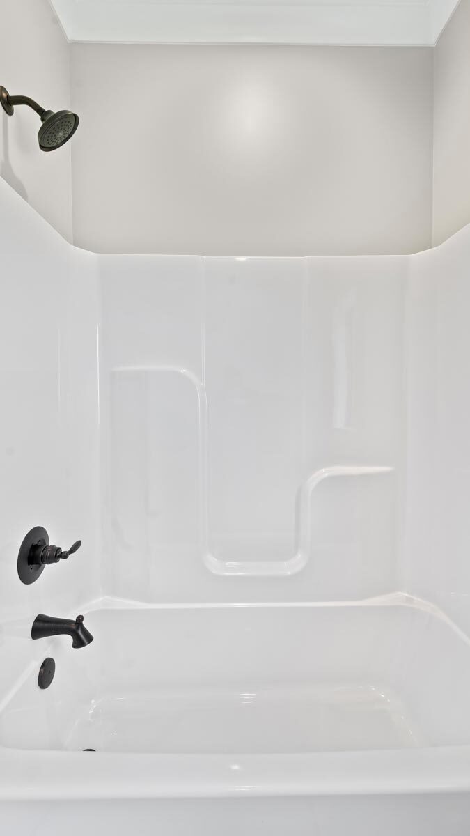 A tub and shower combo with wrought iron fixtures.