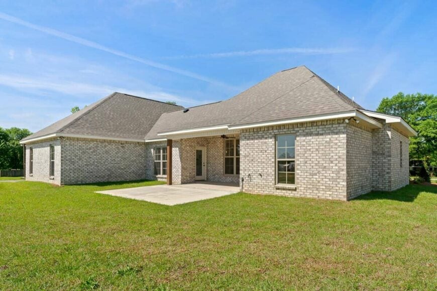 Rear exterior view with brick walls, hipped roofs, and a covered porch that transitions to a concrete patio.