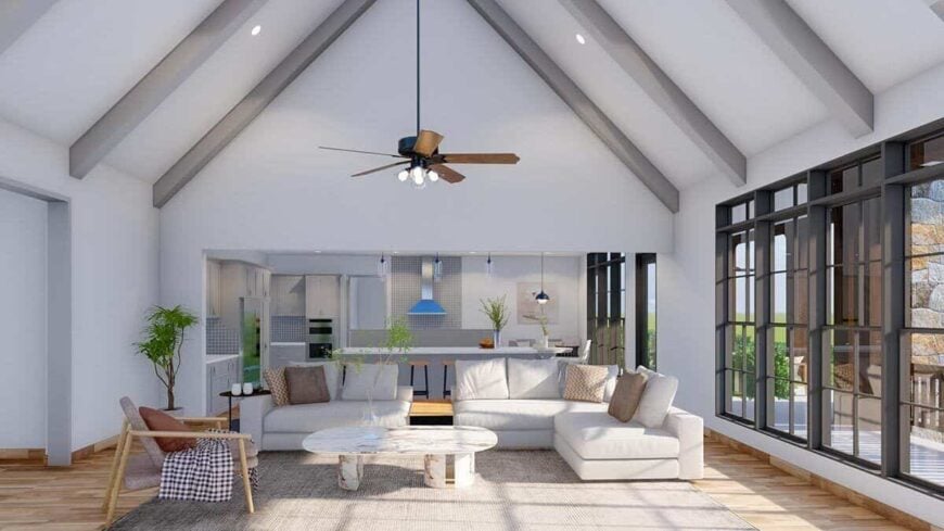 The great room has gray seats, a marble coffee table, and a cathedral ceiling lined with exposed beams.