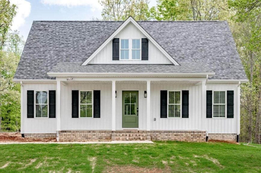 Front exterior view with shuttered windows and a covered entry porch complemented with a brick stoop and a central gable.