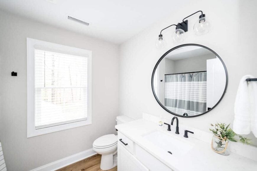 A white framed window brings natural light into this bathroom.