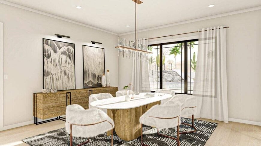 Dining area with an oval dining set, an elegant linear chandelier, a buffet table, and a trio of windows overlooking the pool.