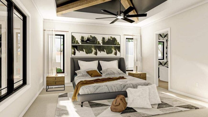 Primary bedroom with a gray wingback bed, wooden nightstands, and a tray ceiling graced with exposed beams.
