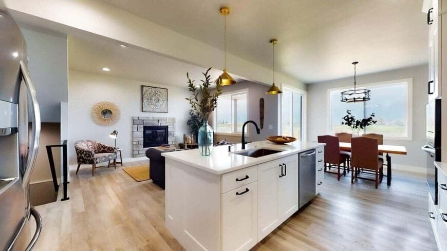 The dining area across the kitchen features a wooden dining set brightened by a round chandelier along with natural light from the glass sliding doors and windows.