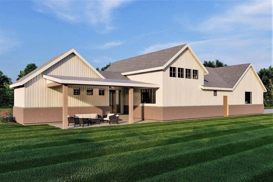 Rear-right rendering with a covered porch furnished with wicker cushioned seats and a matching coffee table.